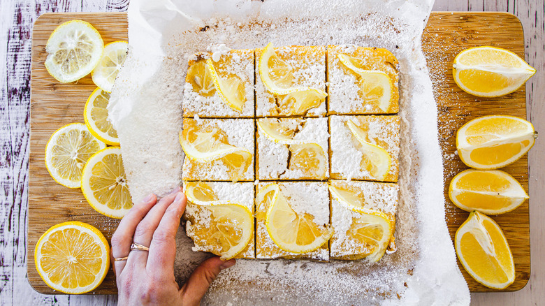 hand grabbing lemon bar squares