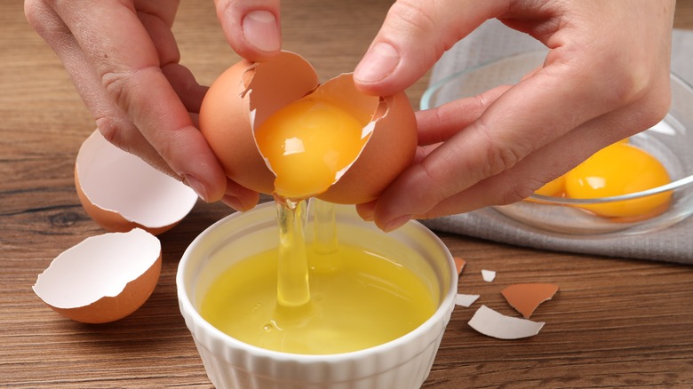 hands separating egg yolk from white