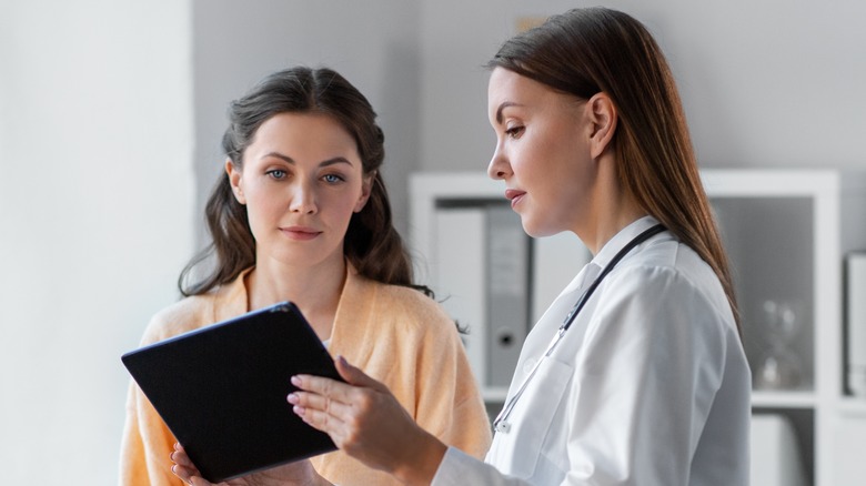 female doctor with tablet talking to female patient