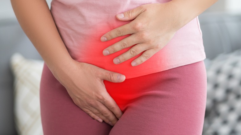 women with pain area highlighted in red holding lower abdomen and vaginal area