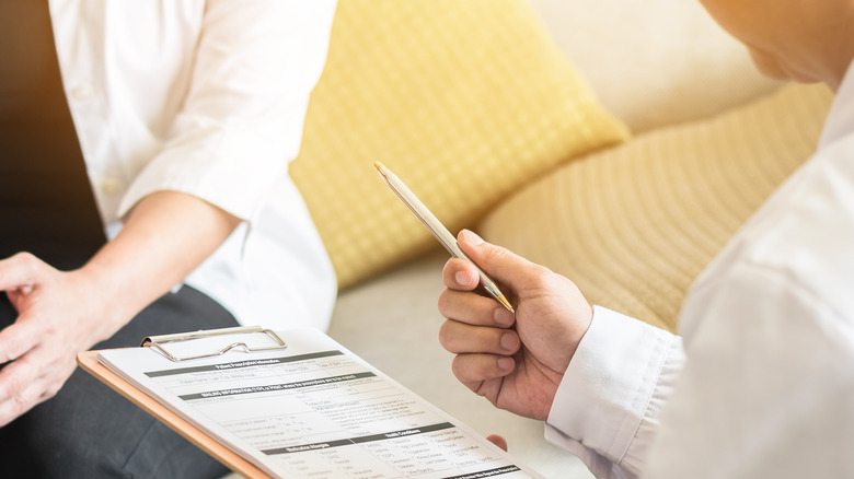 doctor holding a clipboard speaking to a female patient