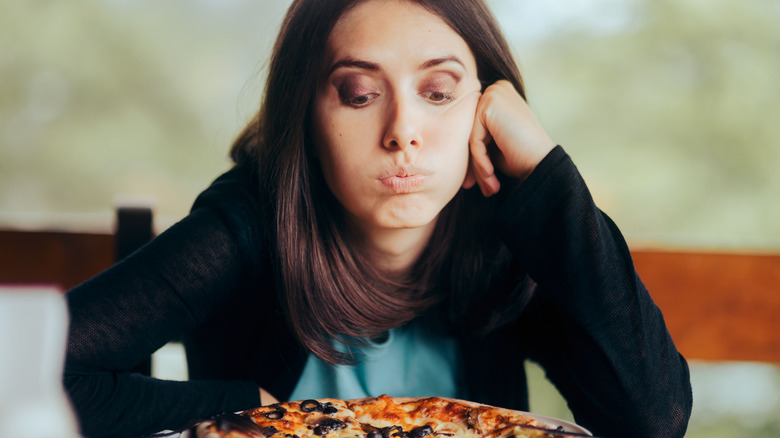 Woman frowning at her pizza