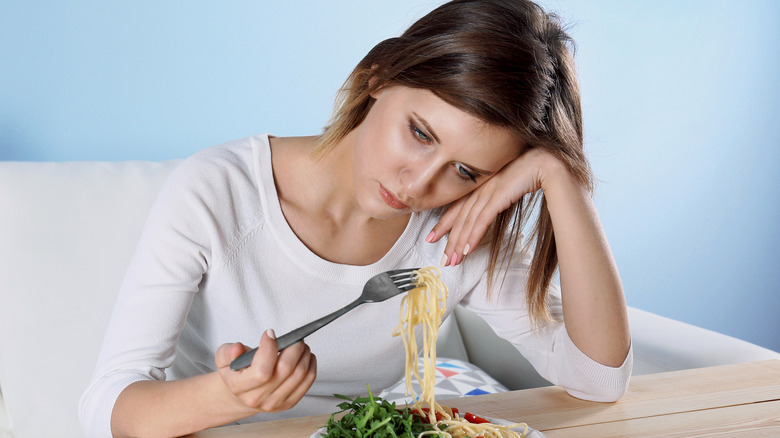 Woman sadly eating her pasta