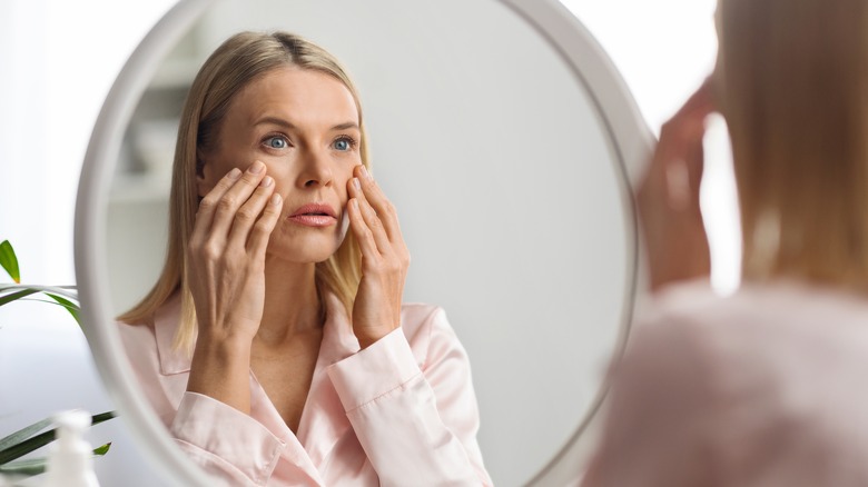 Woman looking concerned at mirror reflection
