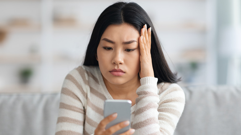 Anxious young woman browsing her phone