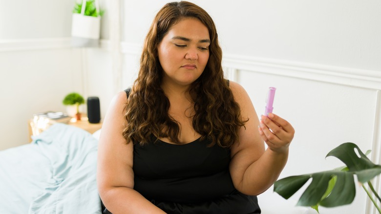 woman unhappily looking at a tampon