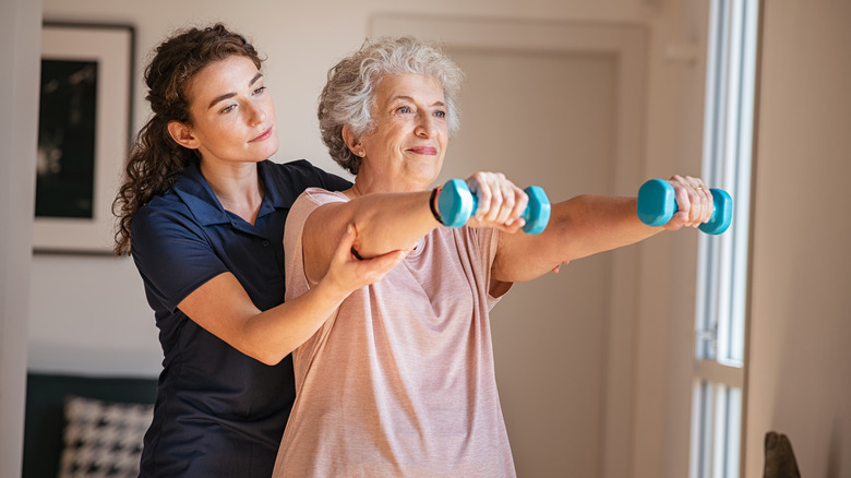 Woman doing arm lifts with help of a physical therapist