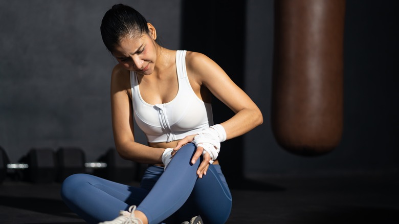 Woman seated on ground with sore knee