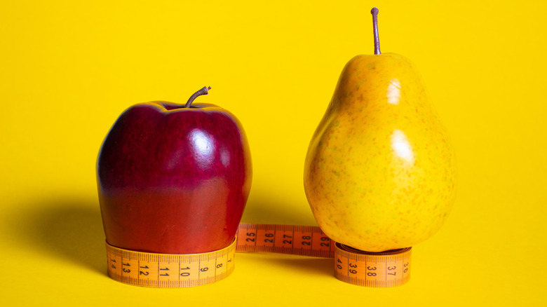 apple and pear sitting on top of measuring tape
