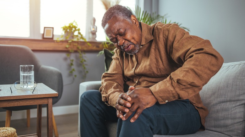 older man holding knee