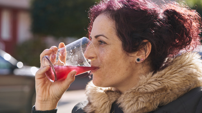 person happily drinking cranberry juice