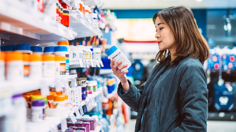 woman looking at supplement bottle in store