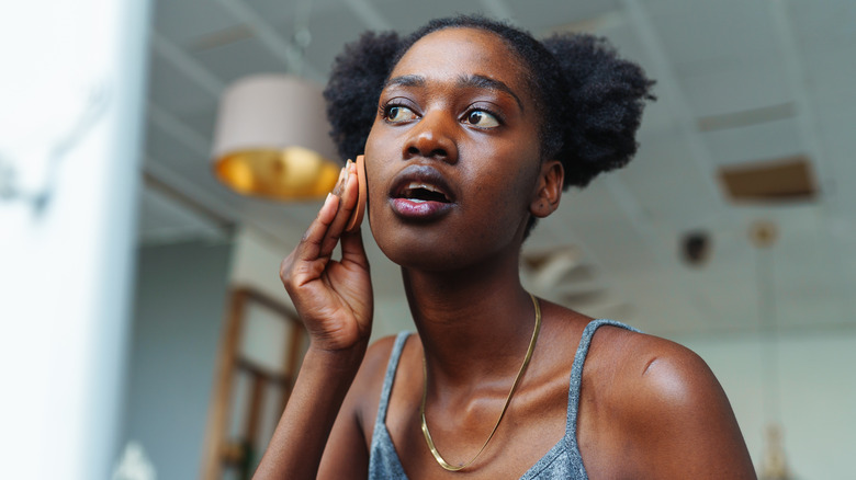 young person applying oil to face