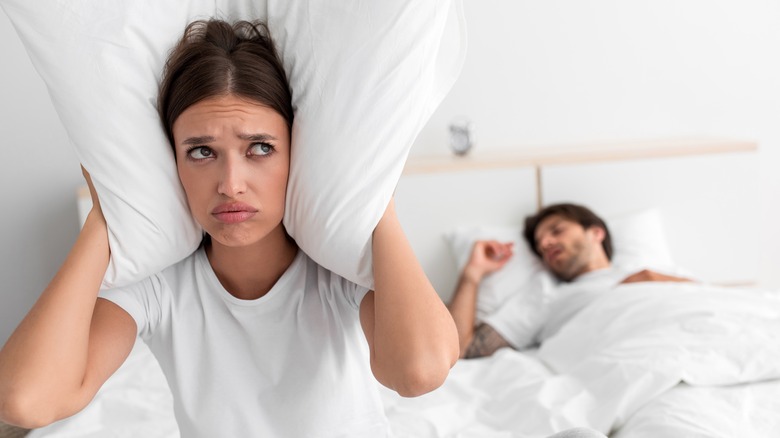 man snoring with awake irritated partner