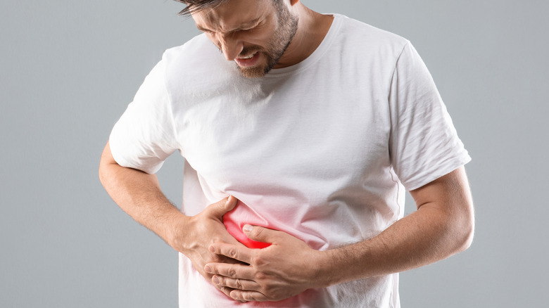 pained man holding ribs and liver