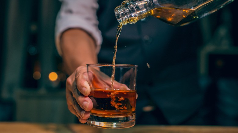 man pouring whiskey glass 