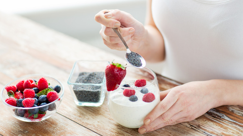 Woman adding a spoonful of chia to yogurt