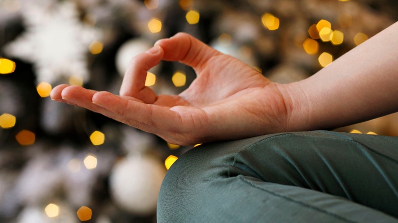 Zen meditation hand with Christmas tree in background