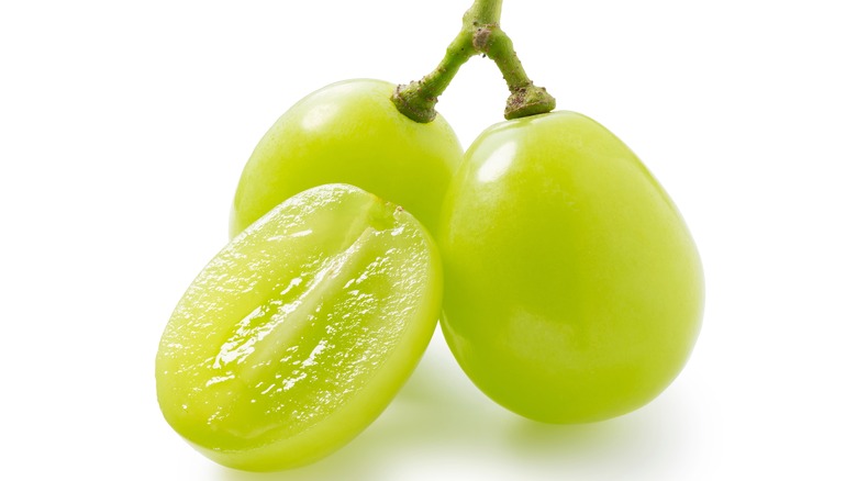 three grapes on a stem one cut in half