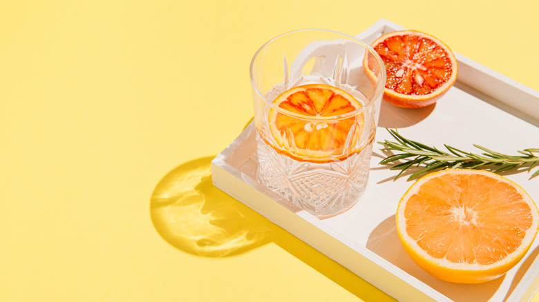 glasses of water with orange slices on a tray with rosemary