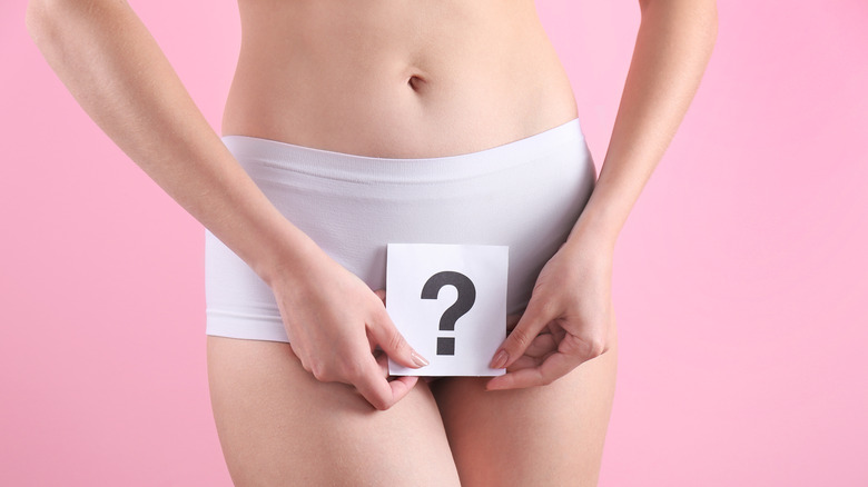 Woman in underwear holding a card with a question mark