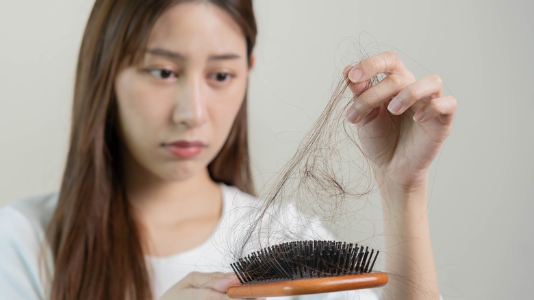 Woman taking hair out of a hairbrush 
