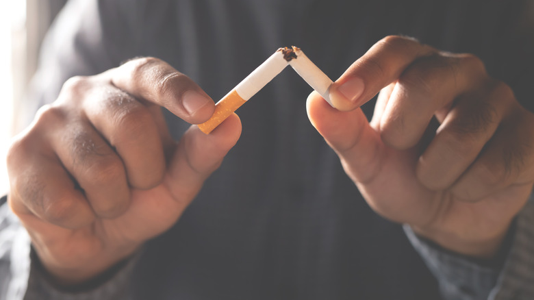 hands holding cigarette that is broken in half