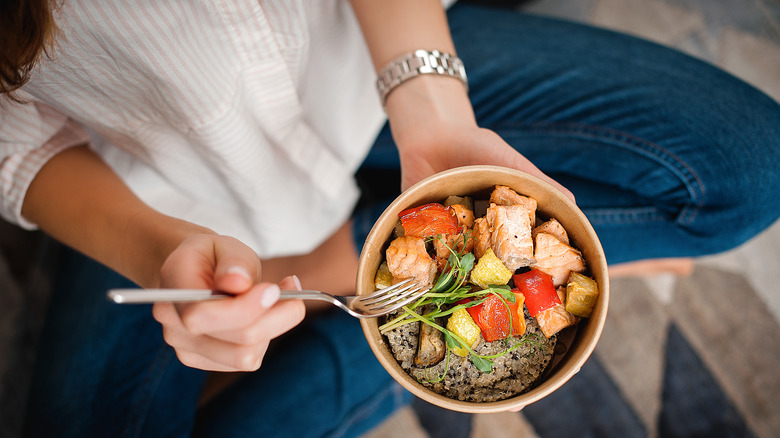 woman holding fork and healthy bowl of food