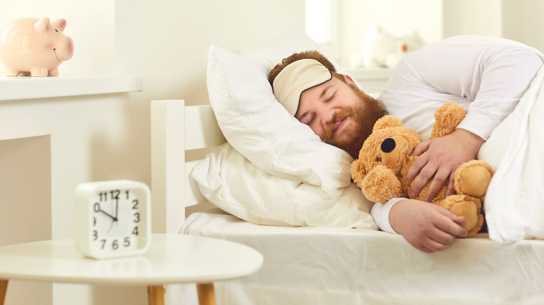 man resting in bed with stuffed teddy bear