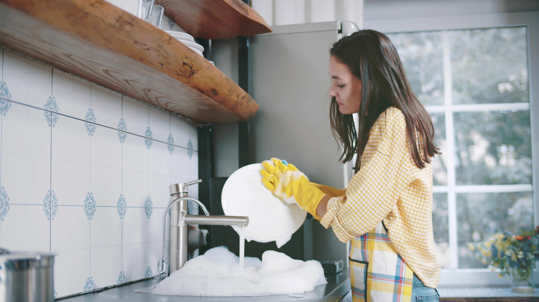 woman washing dishes with gloves on