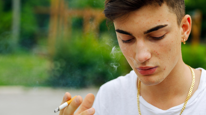 man with acne smoking