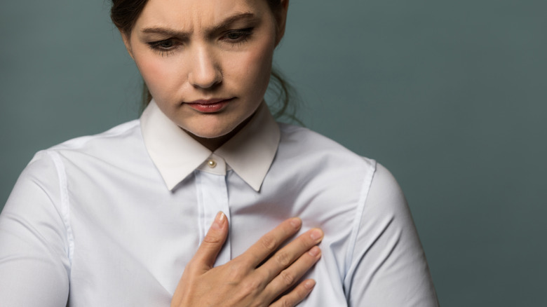 woman holding chest in pain