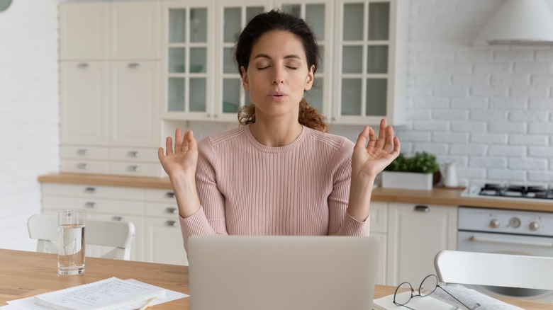 woman looking stressed at computer trying to meditate