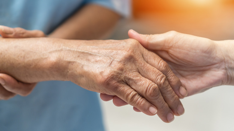 person holding an elderly person's hand indicating pain