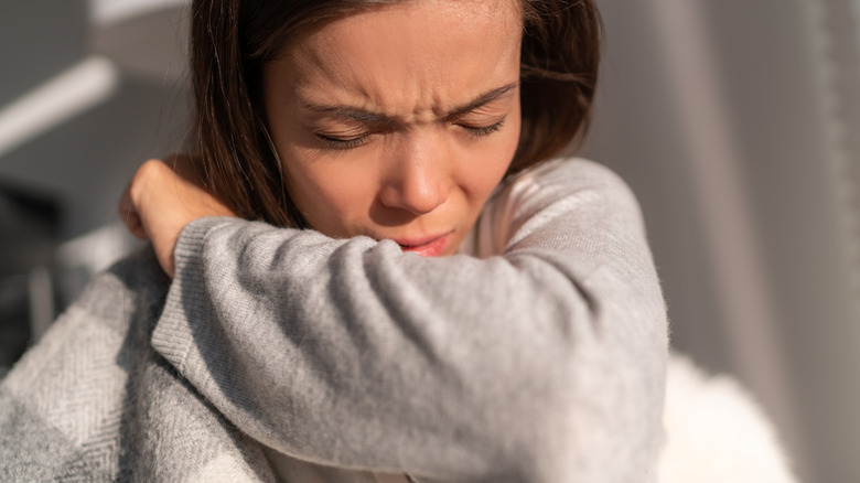 person coughing into their elbow