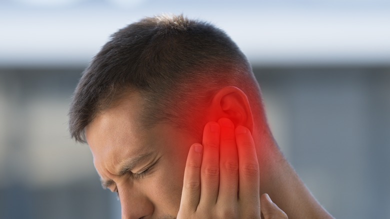 man holding his ear in pain