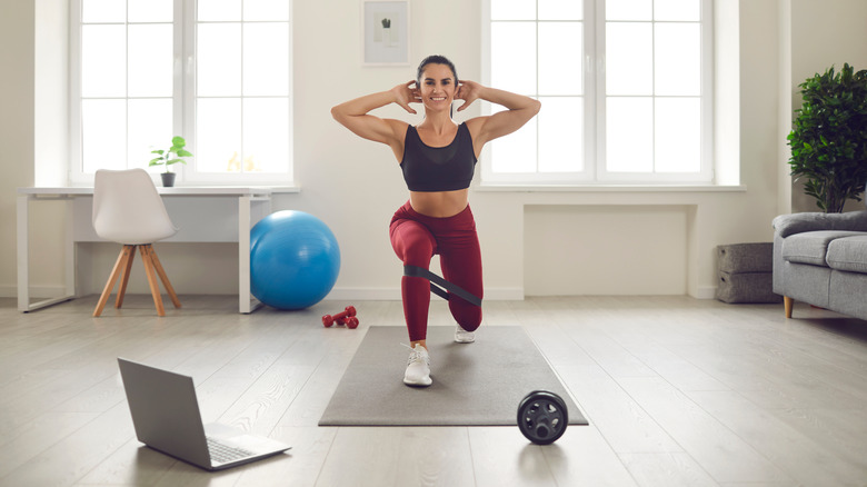 Woman performing reverse lunge in living room