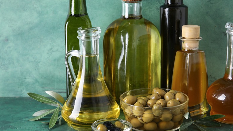 Assorted glassware of olive oil on green background