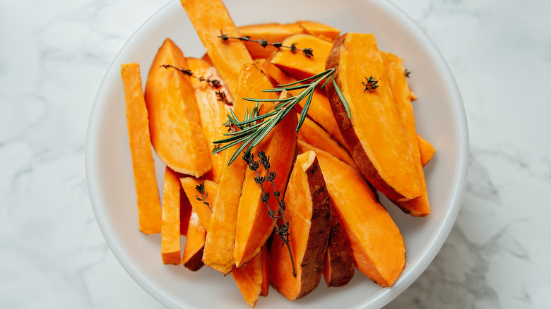 Raw sweet potato wedges in a white bowl