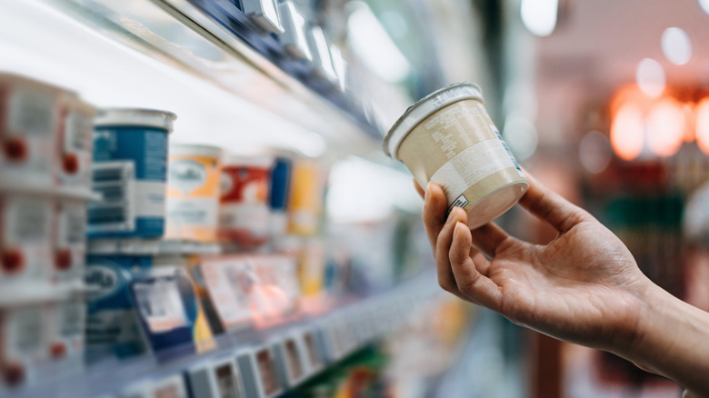 Close-up of a woman's hand shopping for yogurt