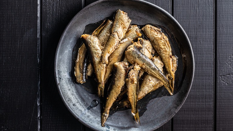 sardines on black plate against black wood table