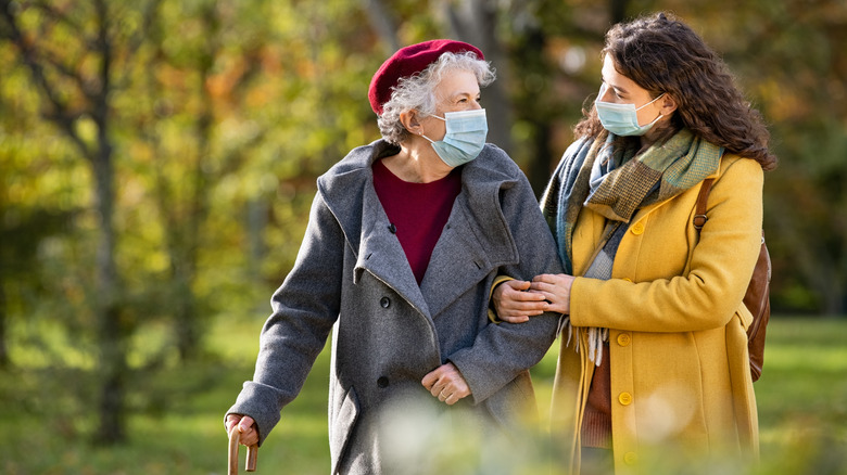 Younger woman helping older woman walk outdoors