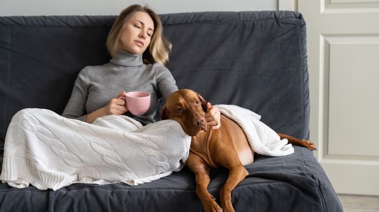 Depressed woman sitting on couch with dog
