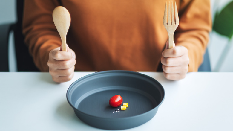 plate with one tomato and two pieces of corn