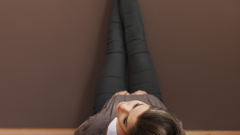 woman lying on floor stretching legs up wall