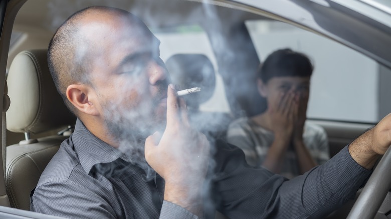 man smoking with wife in car