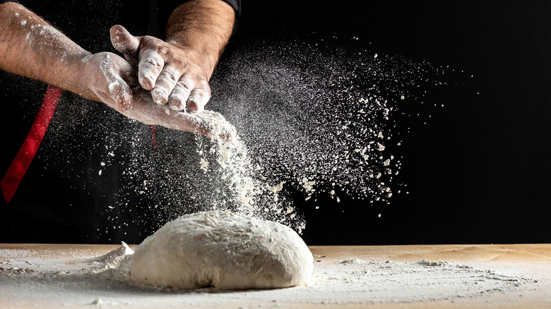 Hands brushing off flour and sending it into the air