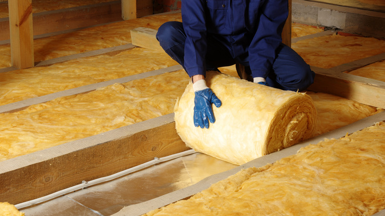 A person holding a roll of insulation