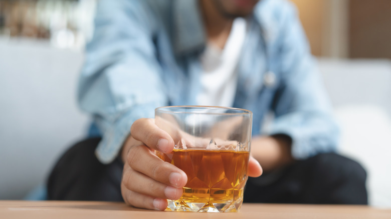 cocktail in glass with man in background holding it