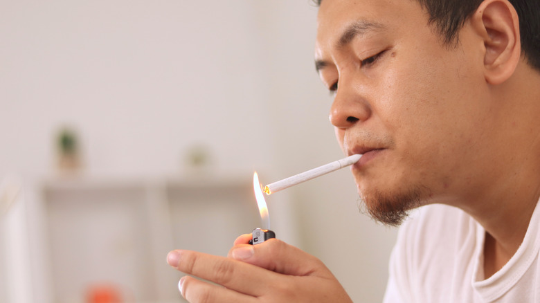 man lighting up cigarette